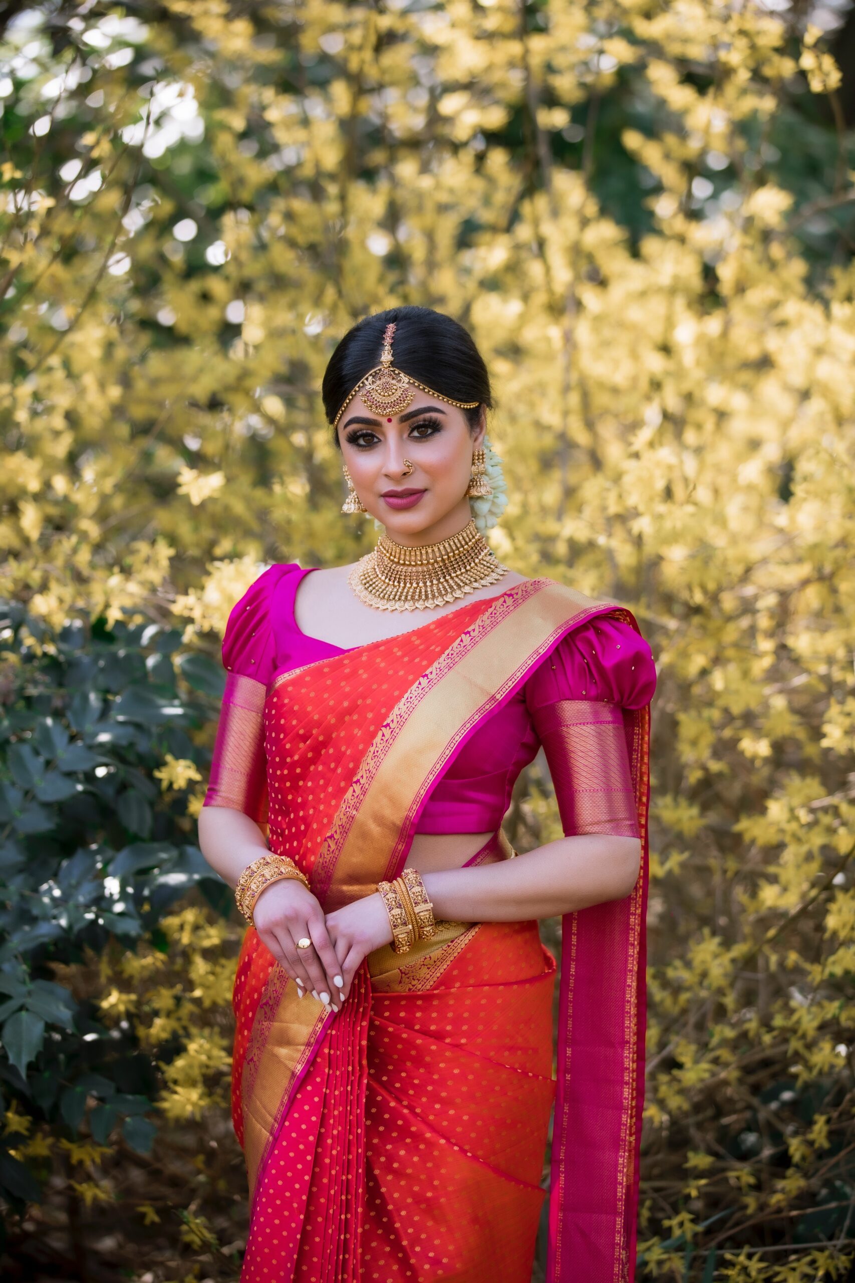 Indian Bride standing in garden wearing orange Saree